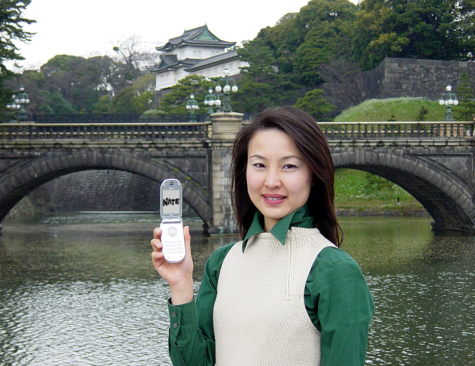 An SK Telecom staff member is shown connecting to the NATE Service in front of a palace in Tokyo, Japan. SK Telecom expanded Wireless Data Automatic Roaming Service area to Japan and twelve provinces in China, starting on April 1. This means the wireless data service-enabled area has now been expanded into three countries (Korea, China and Japan) in Northeast Asia.